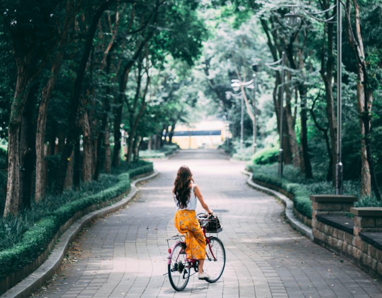 femme sur un vélo se baladant au milieu 'arbre durant la période estivale